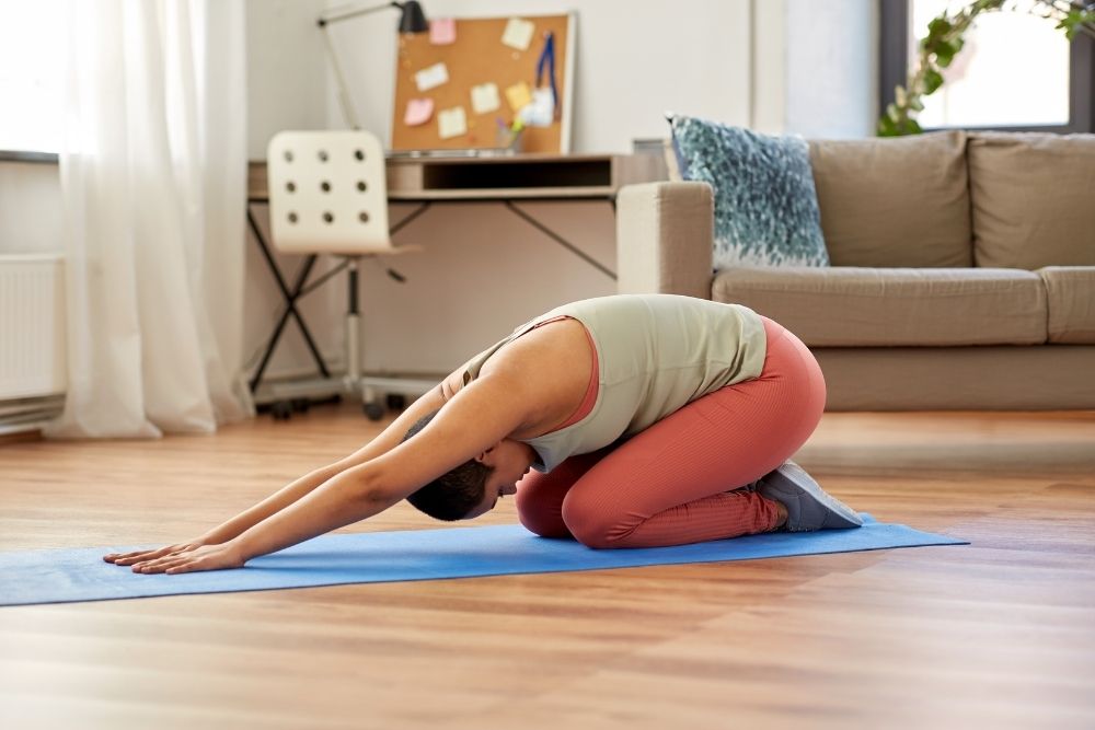 woman doing yoga child pose in a living room