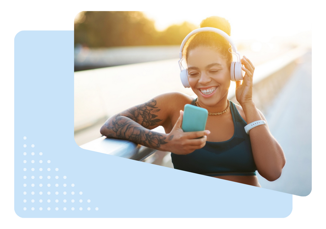 Woman in fitness apparel looking at phone while listening to headphones